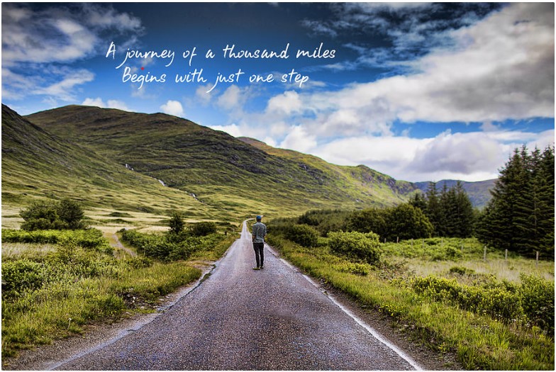 person standing in the middle of a long, straight country road