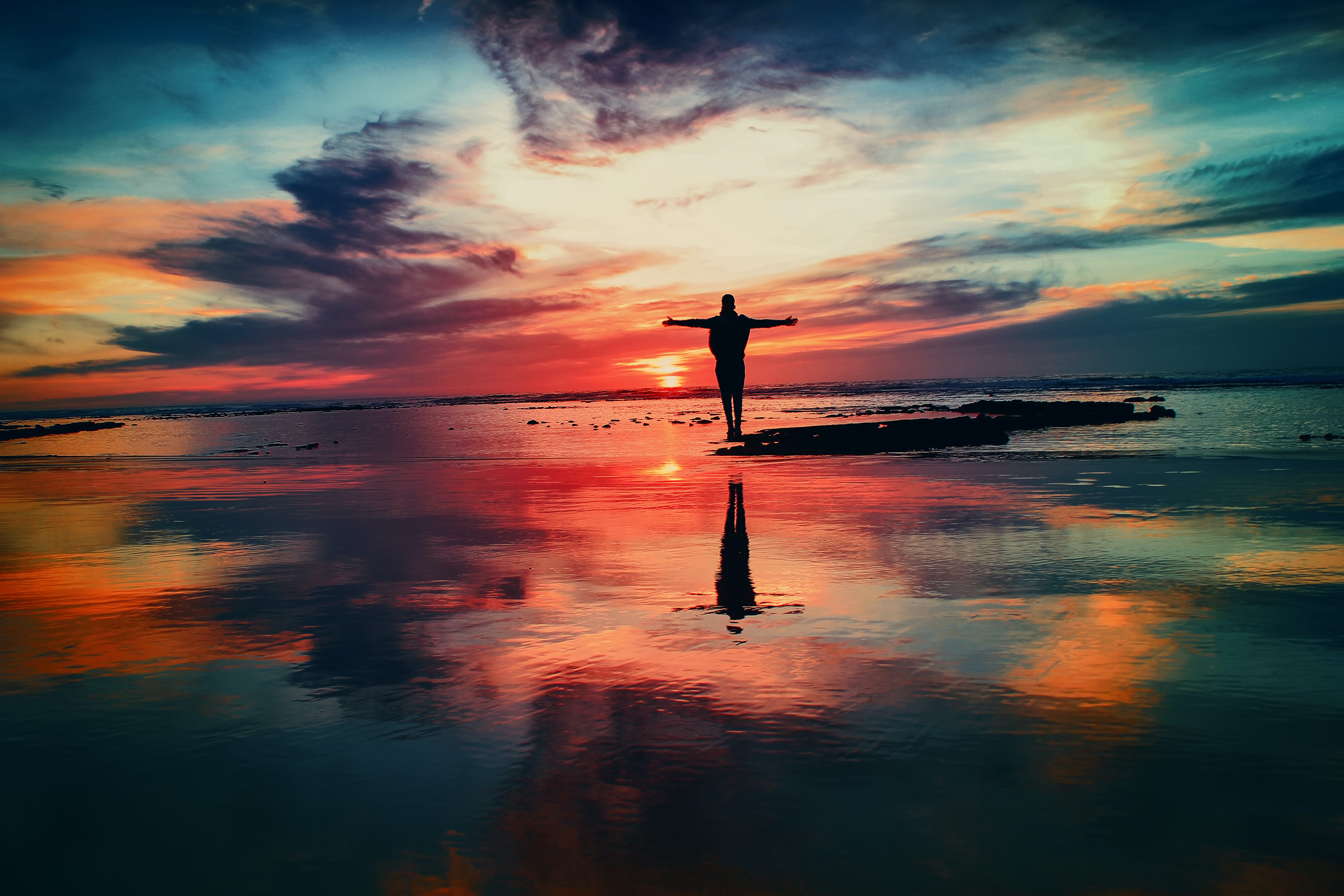 silhouette of a person staring at the sunset surrounded by water