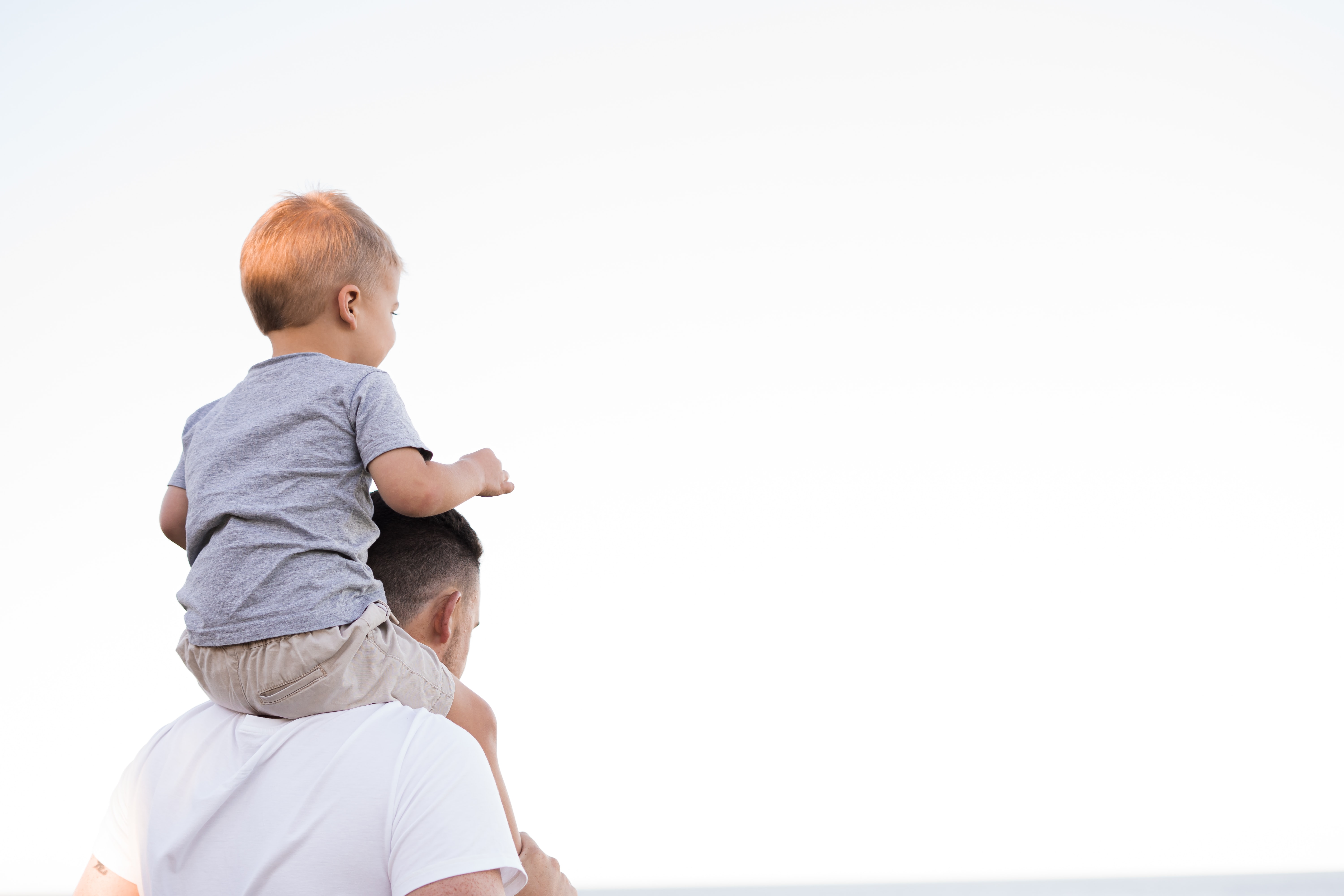 A man walking with a child sitting on his shoulders