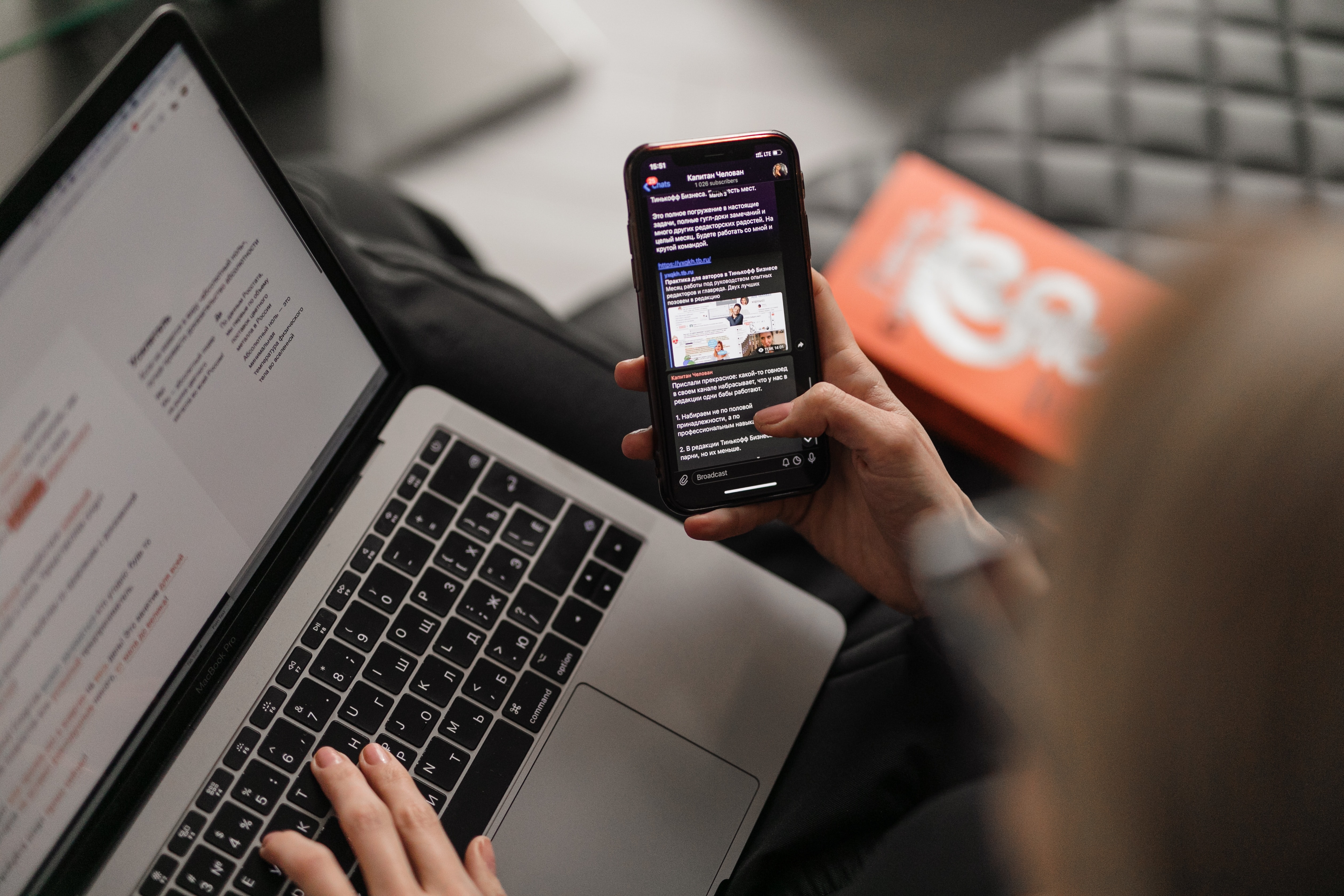 Photo of a person using a smartphone and a laptop computer at the same time