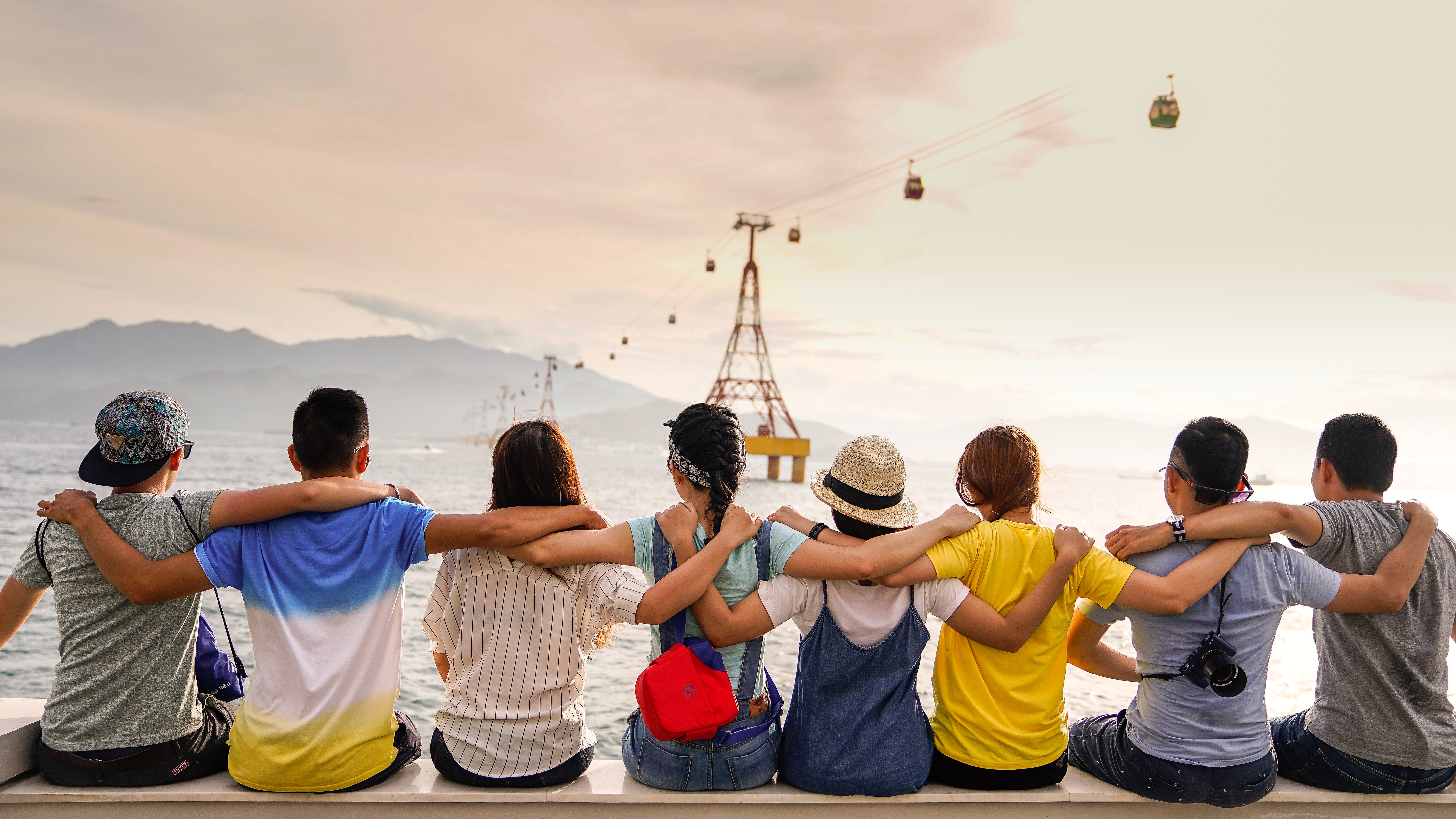 young people sitting on the edge of a dock looking out towards the water